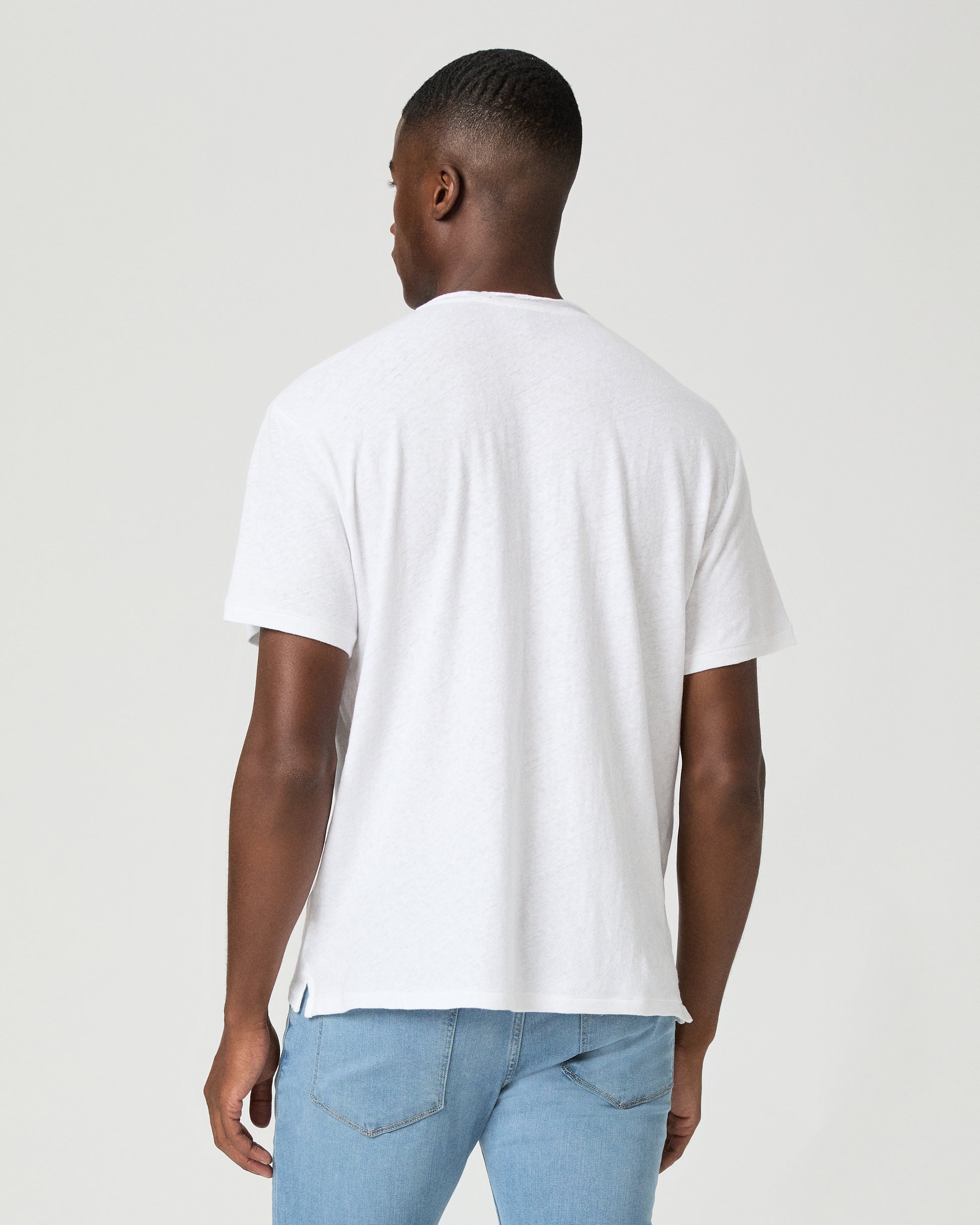 Man wearing a plain white t-shirt and light blue jeans against a white background
