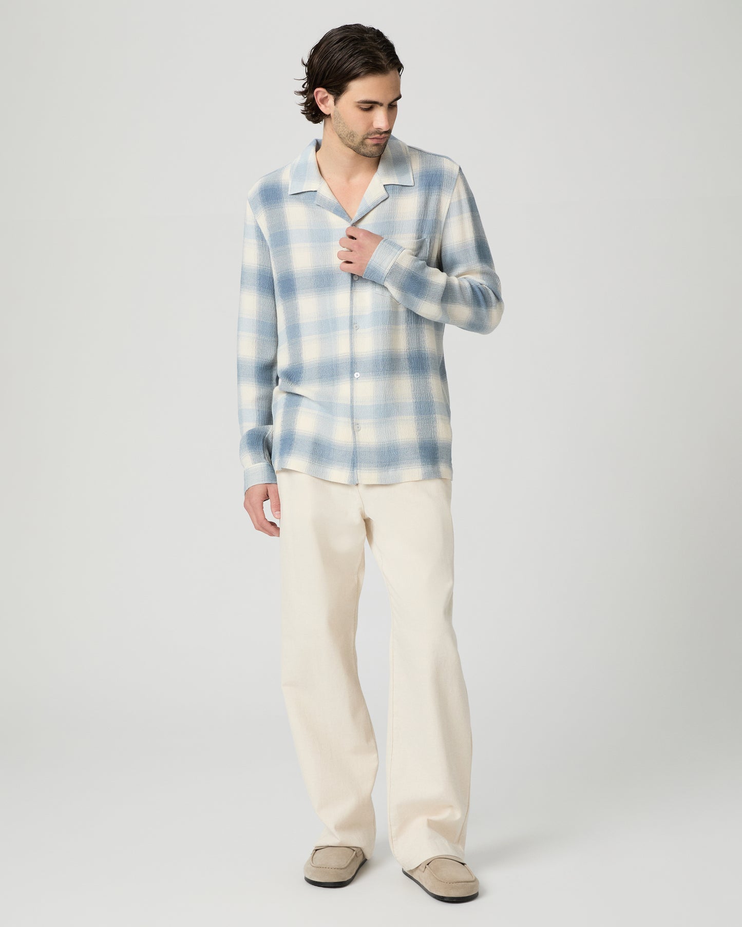 Man wearing a blue and white checkered shirt against a plain background