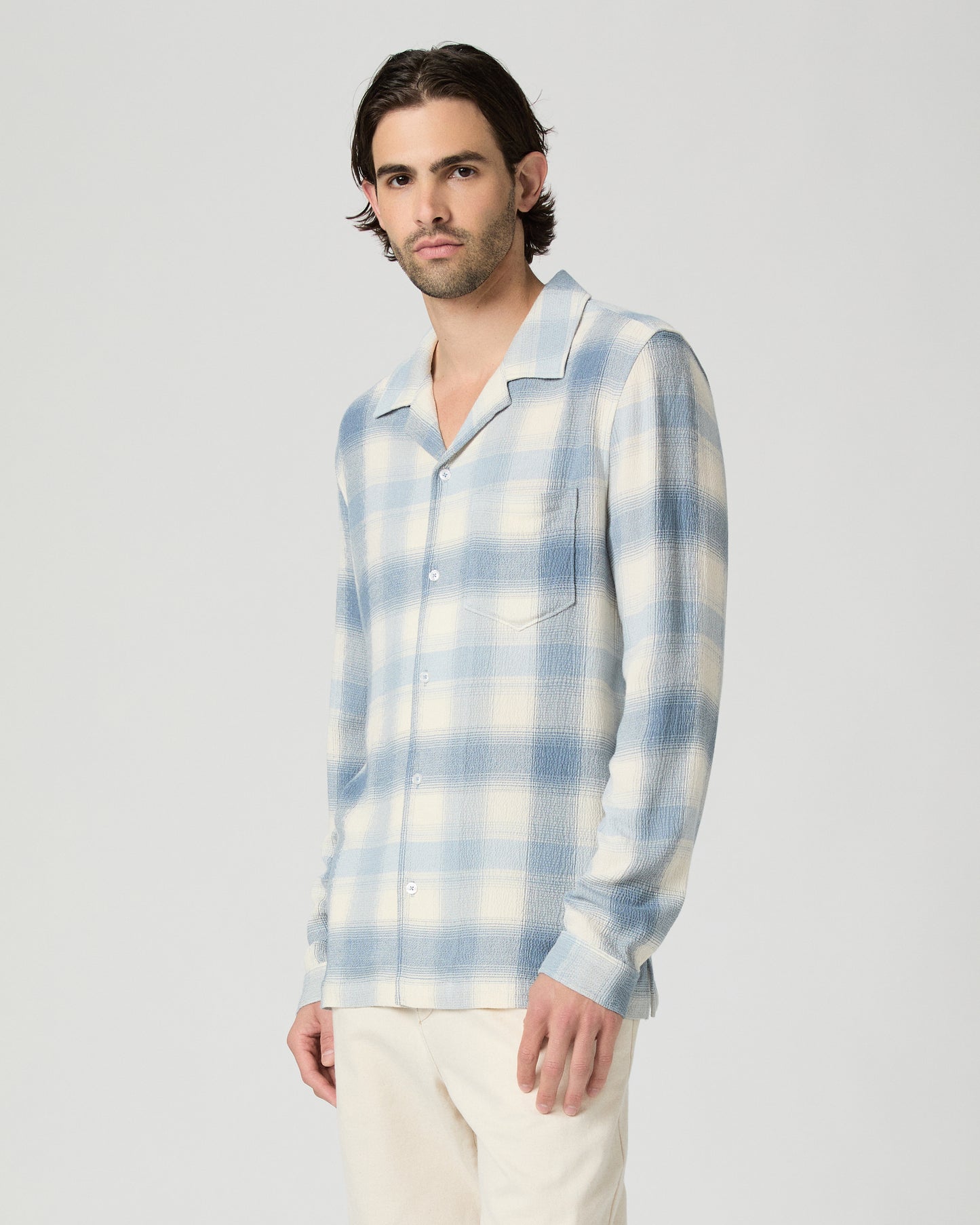 Man wearing a blue and white checkered shirt against a plain background