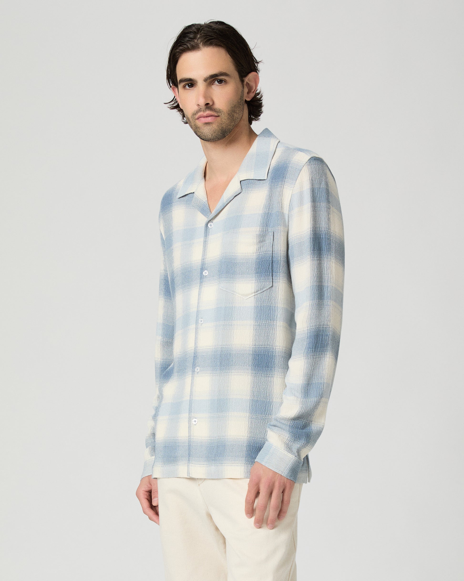 Man wearing a blue and white checkered shirt against a plain background
