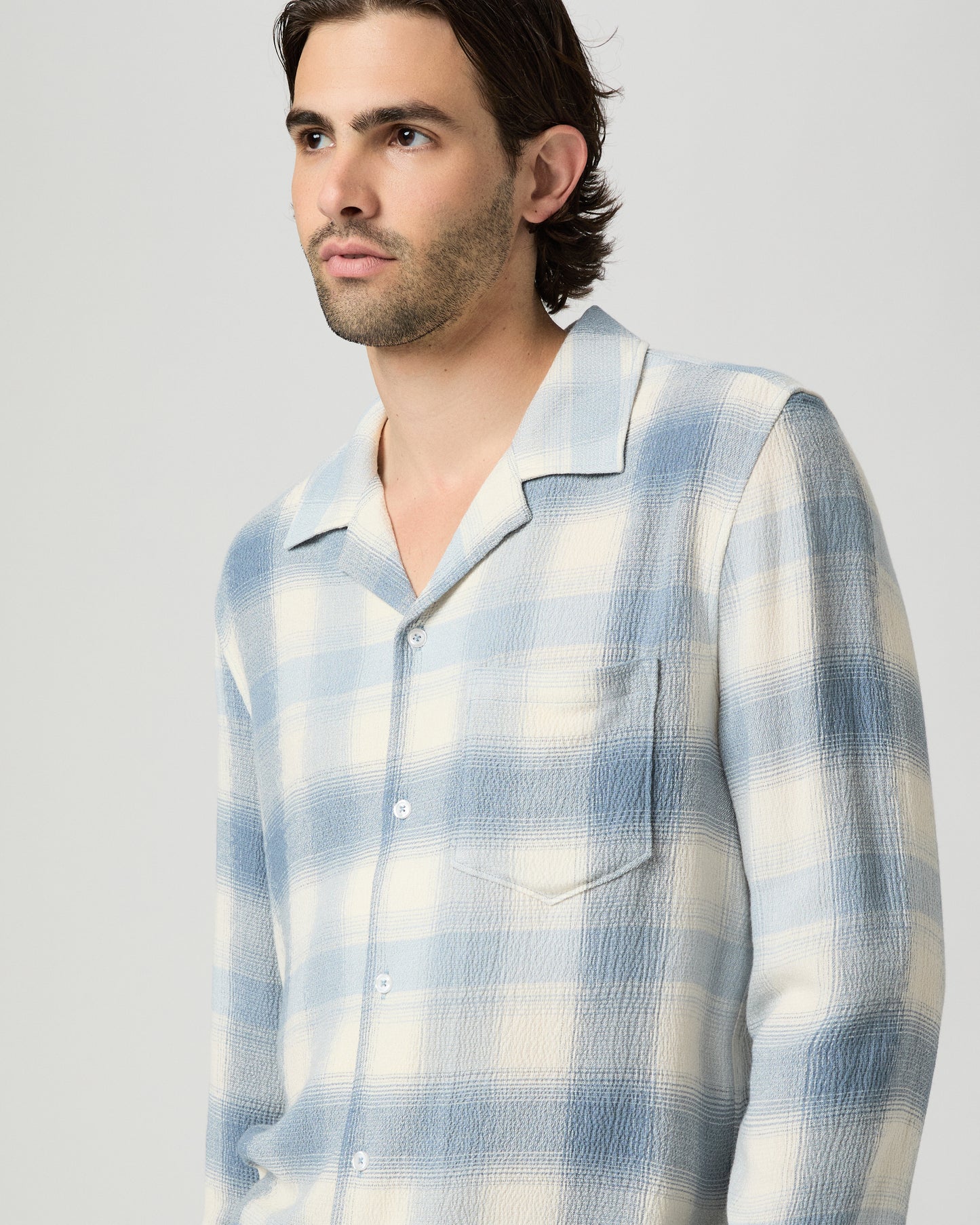 Man wearing a blue and white checkered shirt against a plain background