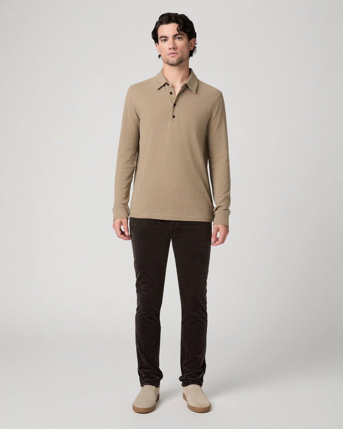 Man wearing beige top and brown pants against a white background