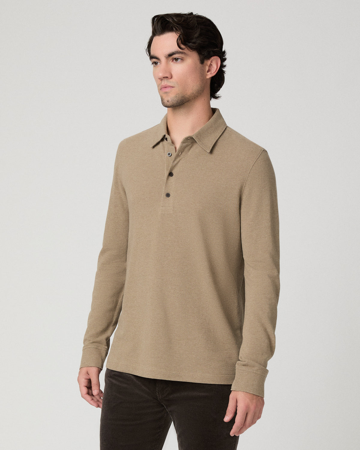 Man wearing beige top and brown pants against a white background