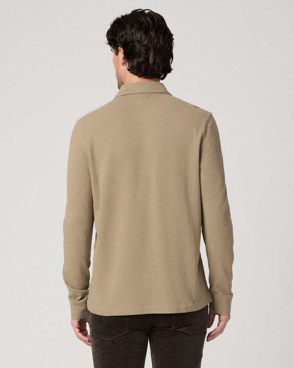 Man wearing beige top and brown pants against a white background