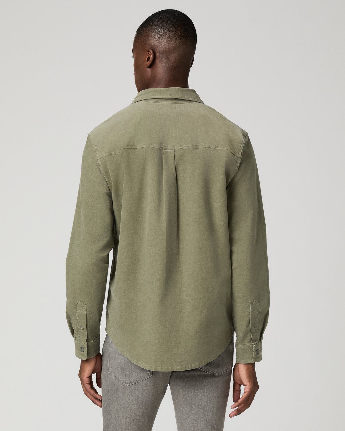 Close-up back view of a man wearing the sage green corduroy shirt, showing the back yoke seam and box pleat detail.