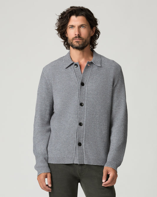 Front view of a man standing with arms crossed, wearing the heather gray ribbed-knit Spokane Cardigan buttoned to the collar over dark olive trousers and black leather shoes.