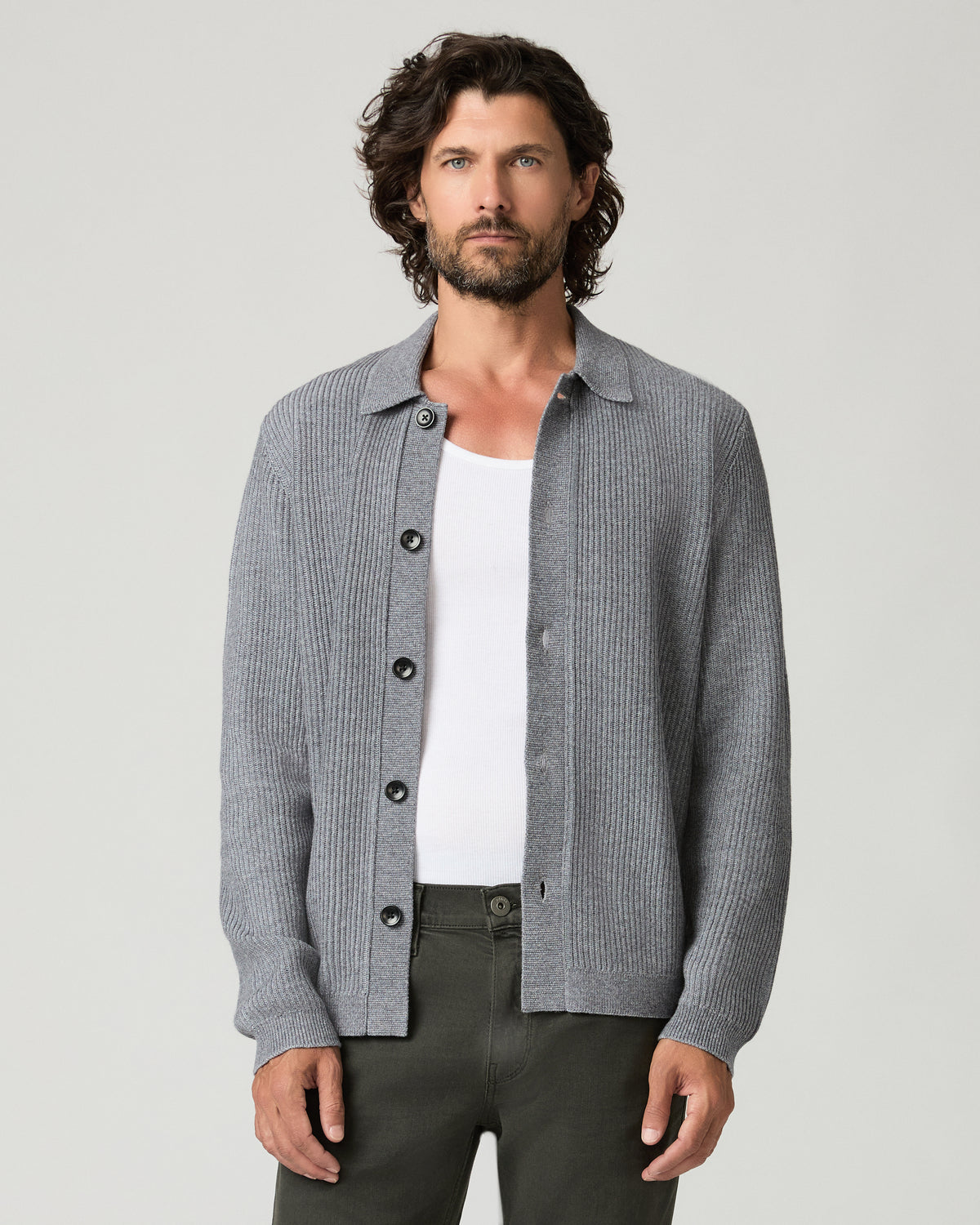 Close-up front view of a man wearing the heather gray ribbed-knit Spokane Cardigan open at the collar, revealing a white tank top underneath, with dark olive trousers visible at the waist.