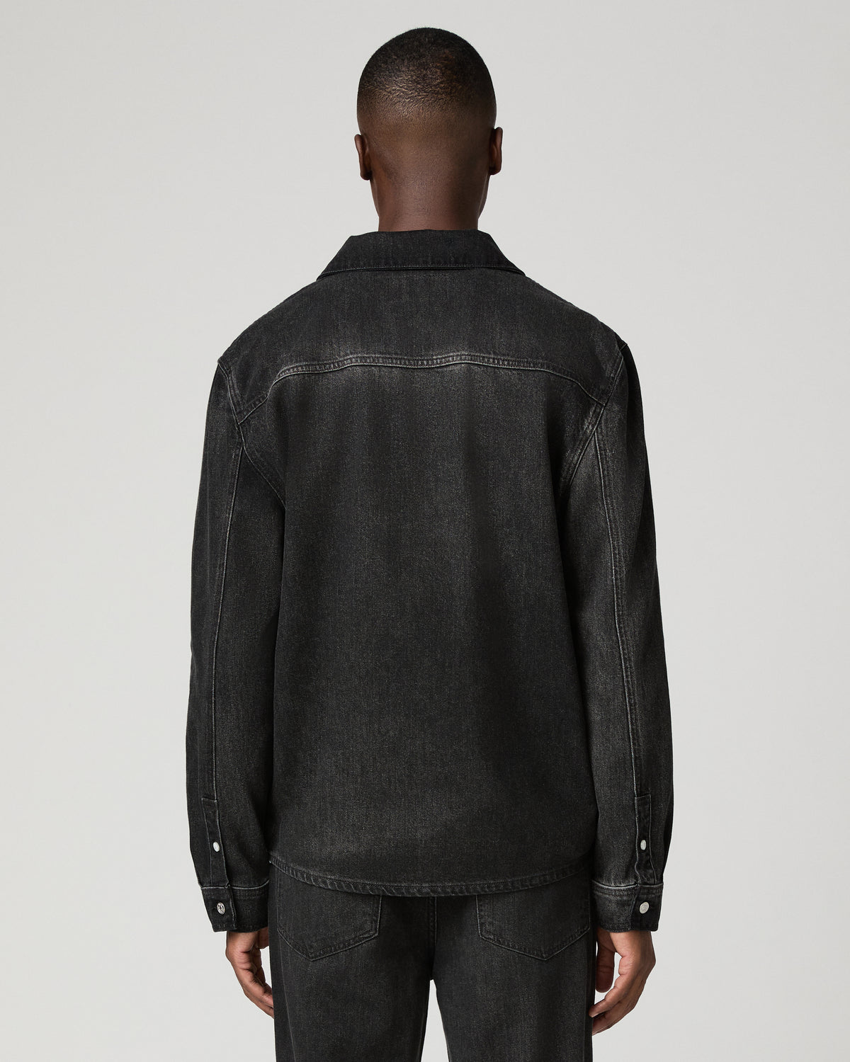 Close-up back view of a man wearing the charcoal denim shirt, showing the back yoke seam and point collar.