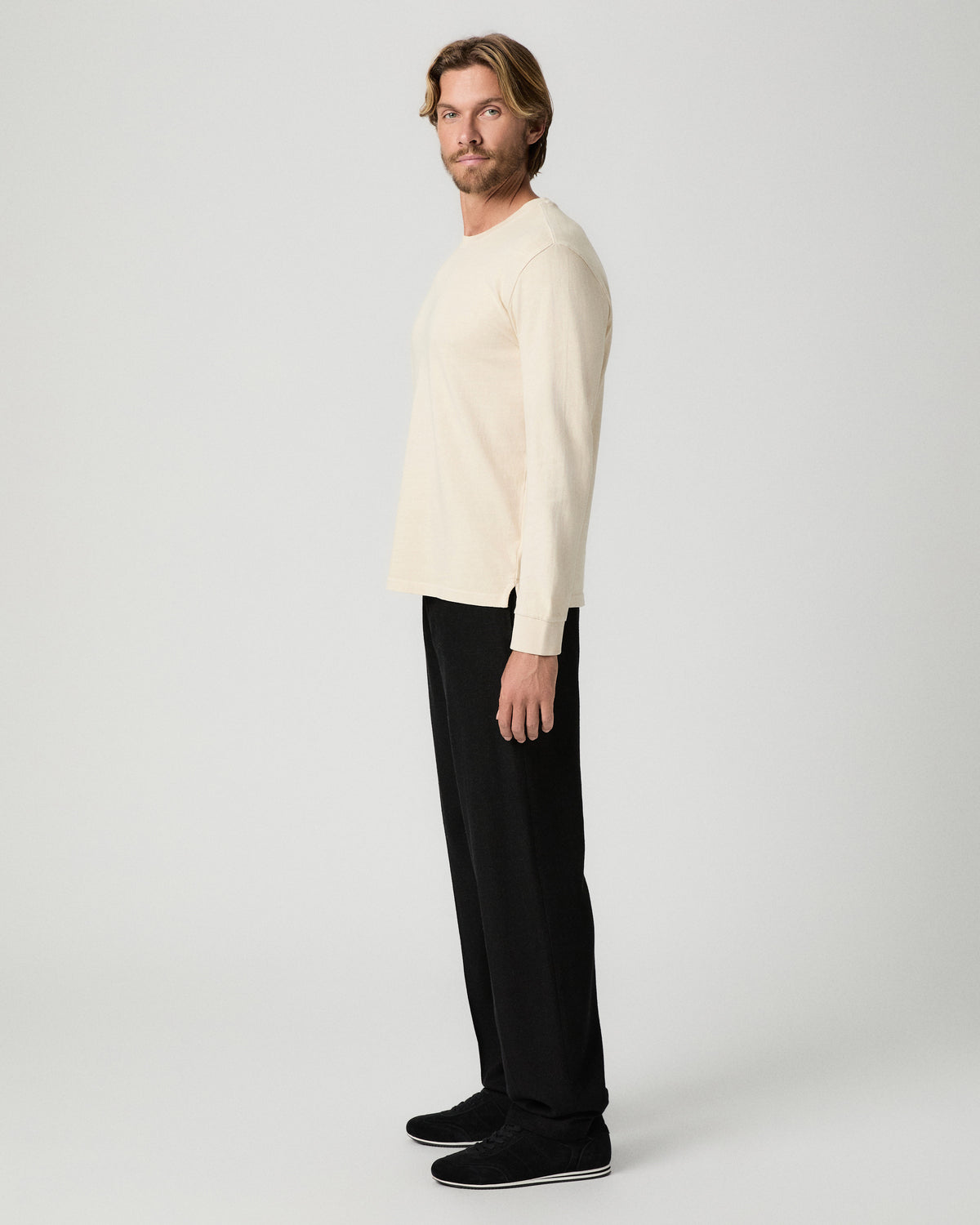 Side profile of model wearing the Norcross Long Sleeve Boxy Tee in Pale Antler with black pants and black shoes