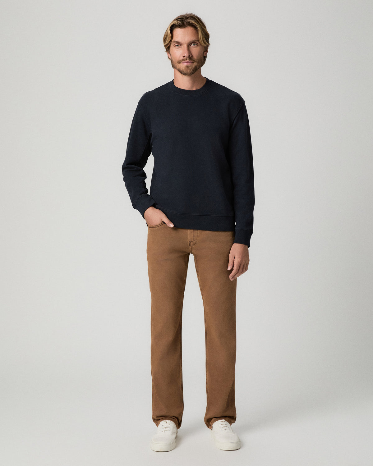 Full-length view of model with one hand in his pocket, wearing the Devlin Crewneck in Deep Anchor with tan pants and white sneakers