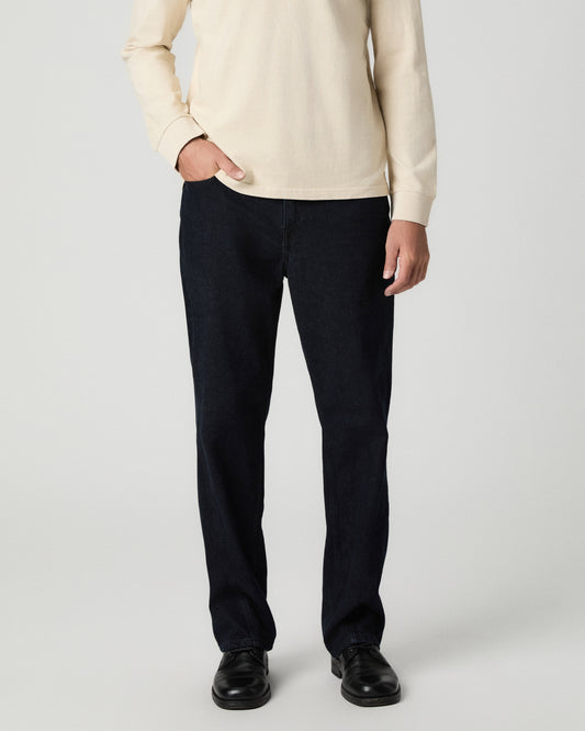 Front view from the waist down of the Doheny 34 Inch Relaxed Straight Jean in Draven, a dark wash, with one hand in the pocket, worn with a cream sweater and black boots