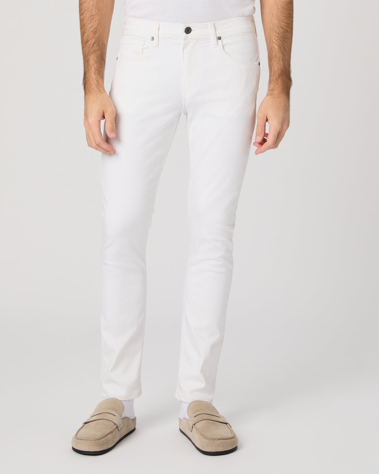 Man wearing a white shirt and white pants on a plain background