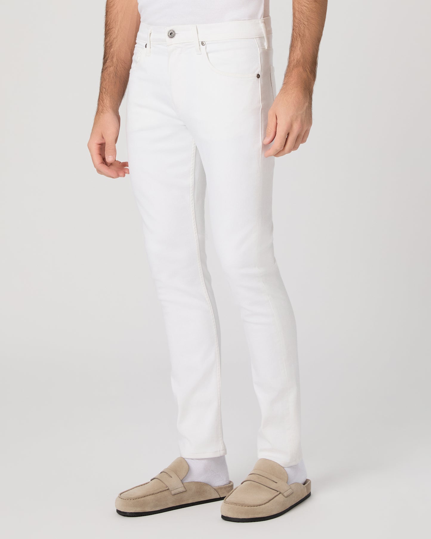 Man wearing a white shirt and white pants on a plain background