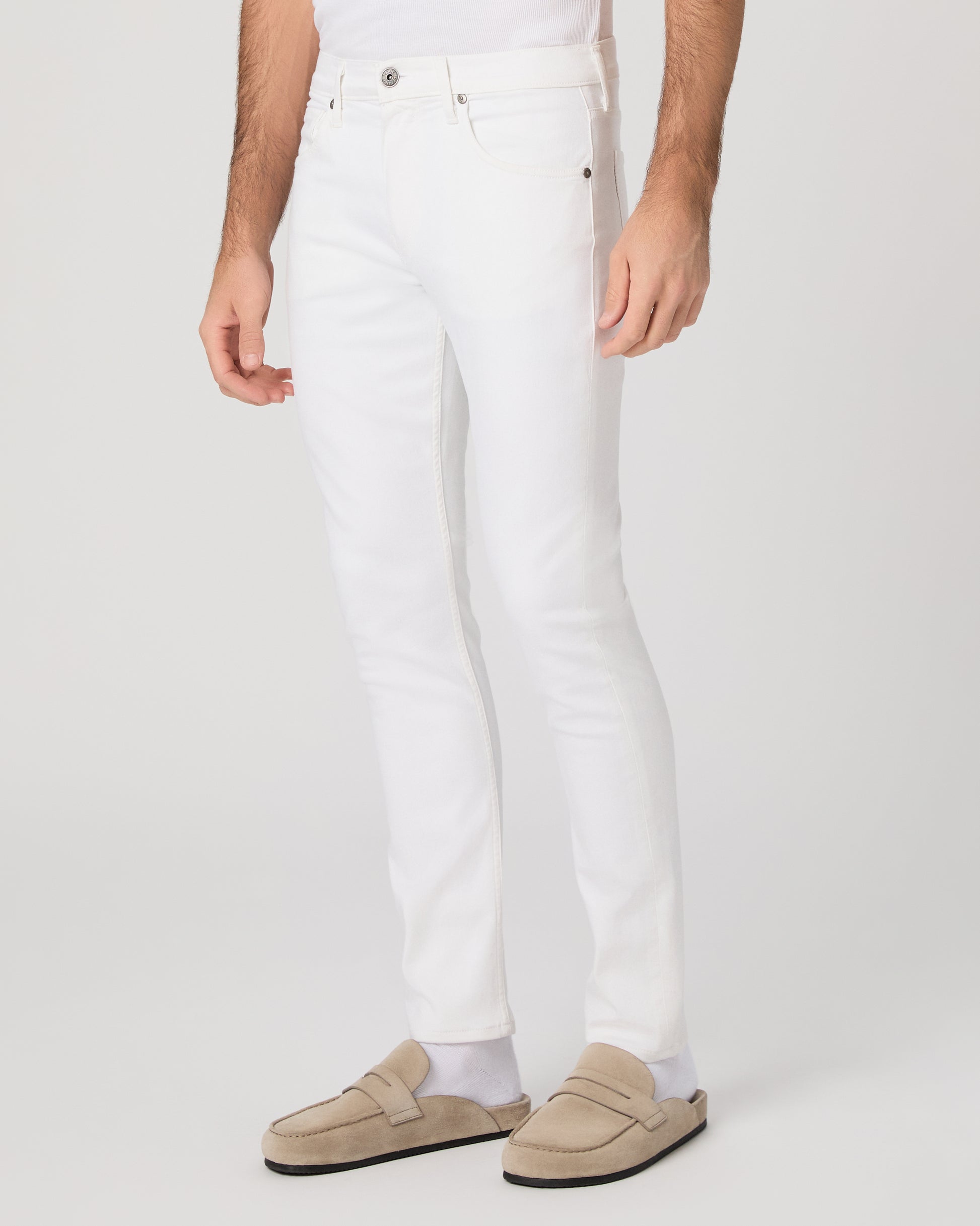 Man wearing a white shirt and white pants on a plain background