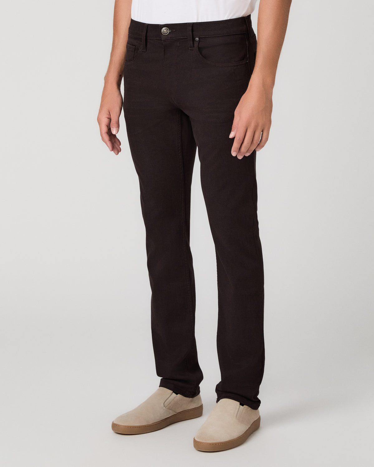 A man modeling a light beige linen button-down shirt with dark brown trousers and beige loafers, standing against a neutral light gray studio background.