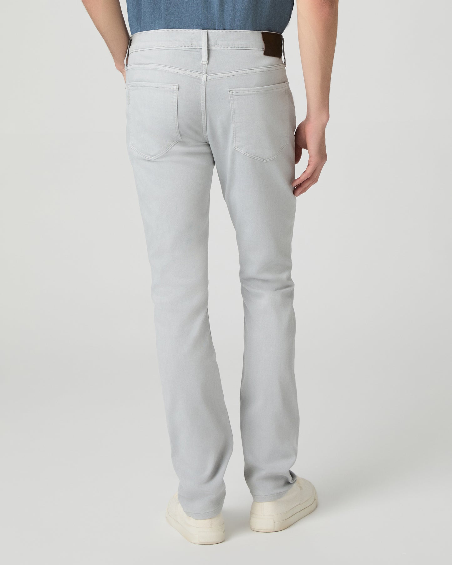 Man wearing a blue t-shirt and gray pants on a white background