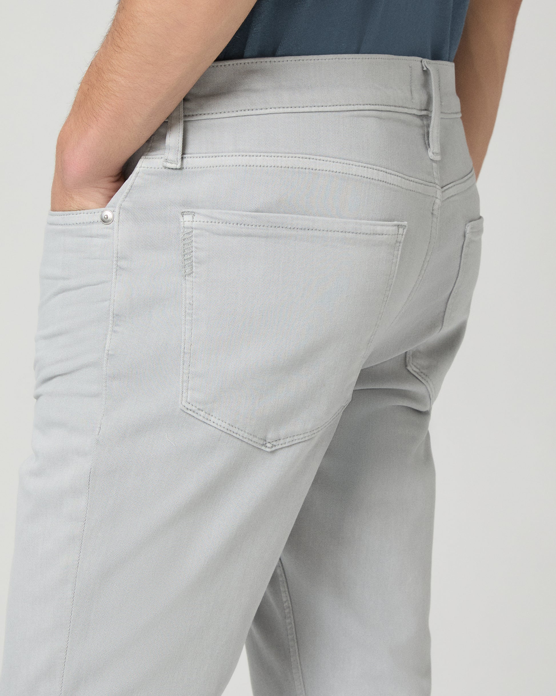 Man wearing a blue t-shirt and gray pants on a white background