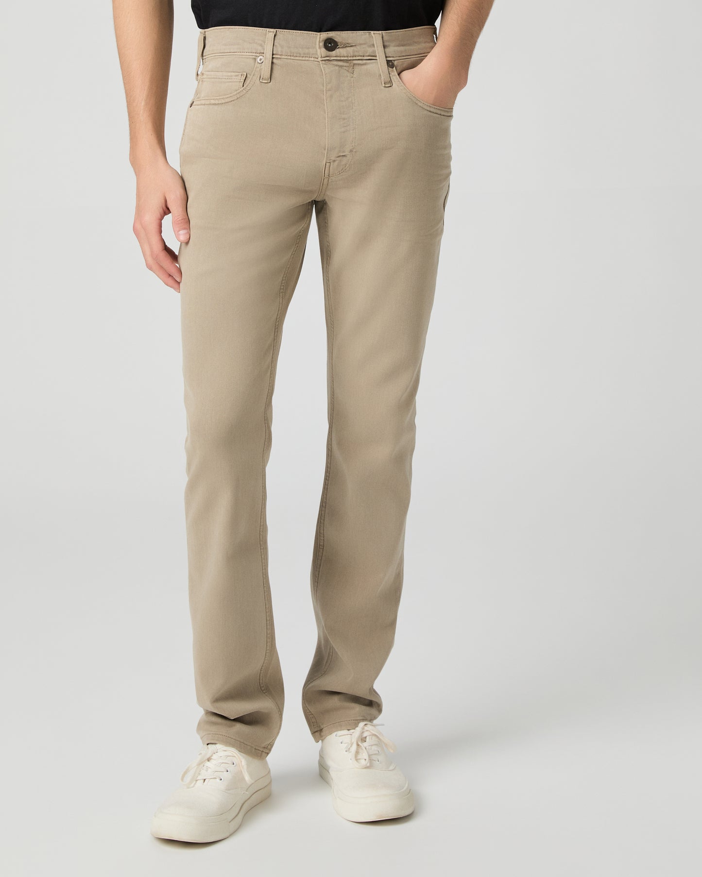 Man wearing a black t-shirt, beige pants, and white shoes on a white background