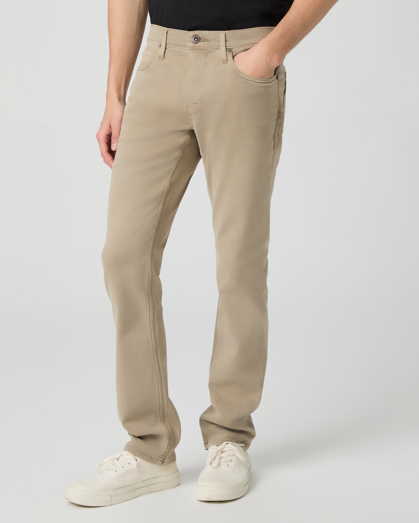 Man wearing a black t-shirt, beige pants, and white shoes on a white background