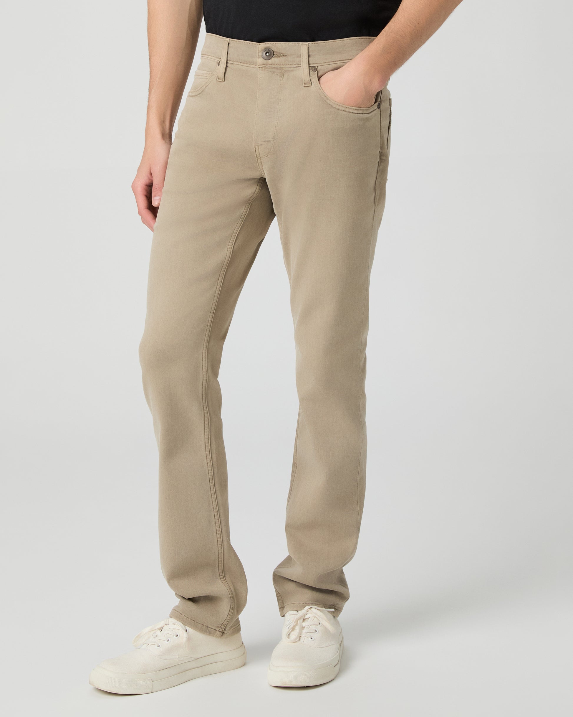 Man wearing a black t-shirt, beige pants, and white shoes on a white background