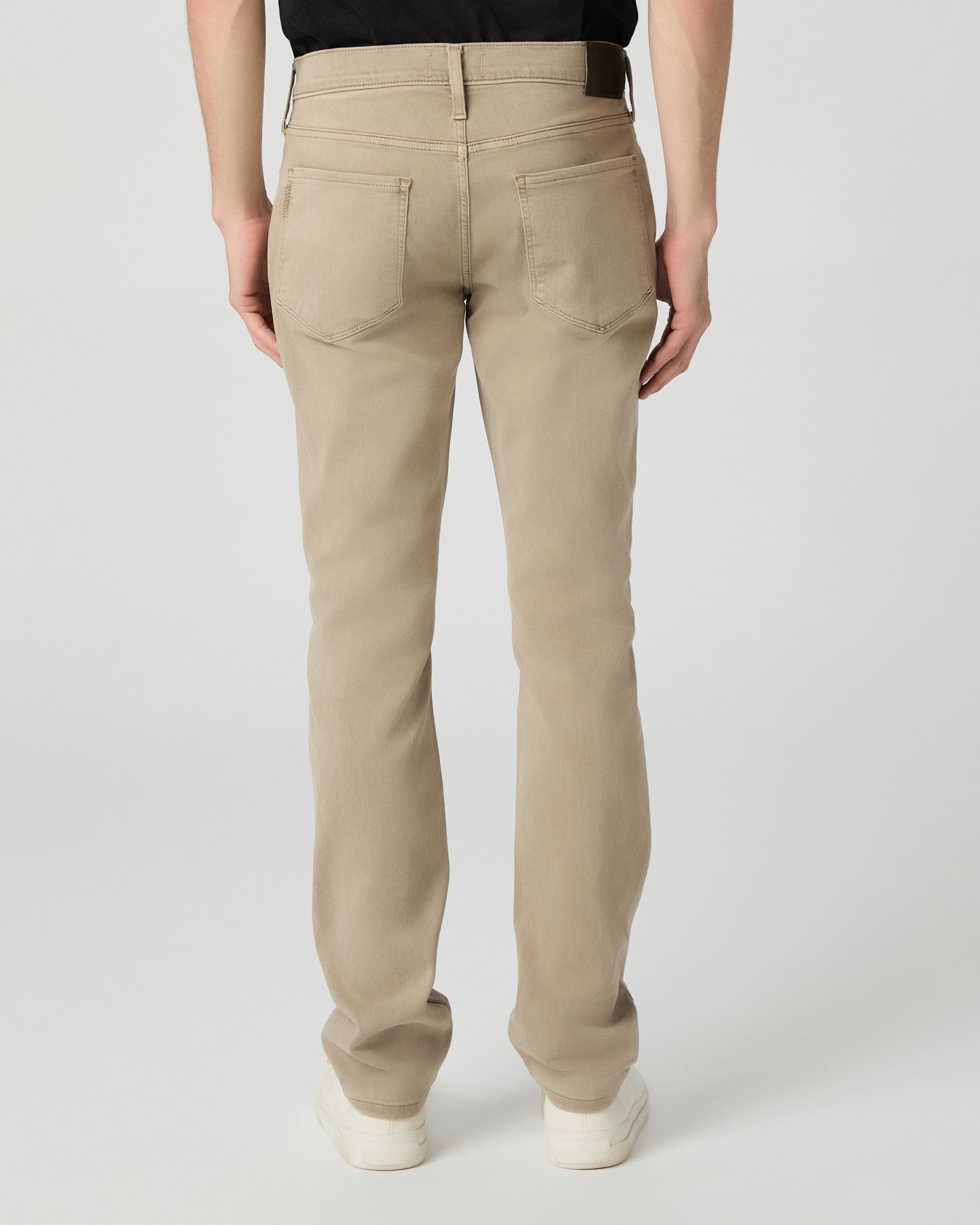 Man wearing a black t-shirt, beige pants, and white shoes on a white background