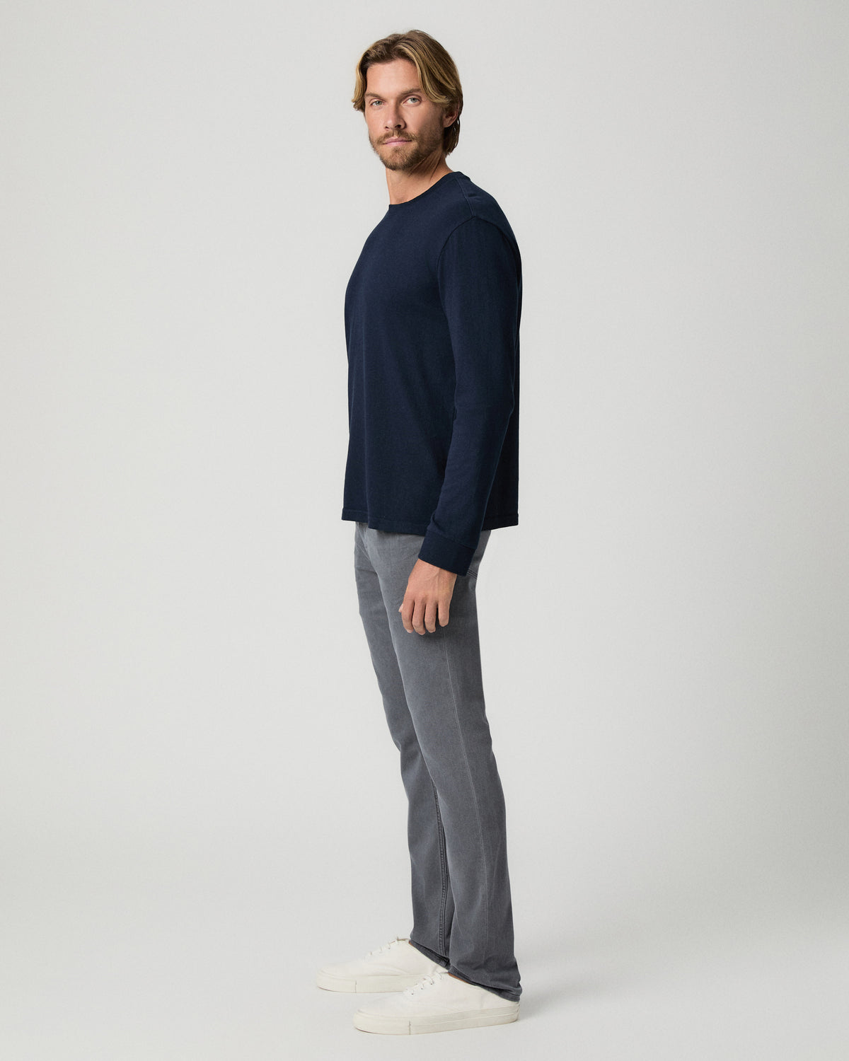 Side profile of model wearing a navy long-sleeve top with the Lennox 32 Inch Slim Jean in Vintage Icy River and white sneakers