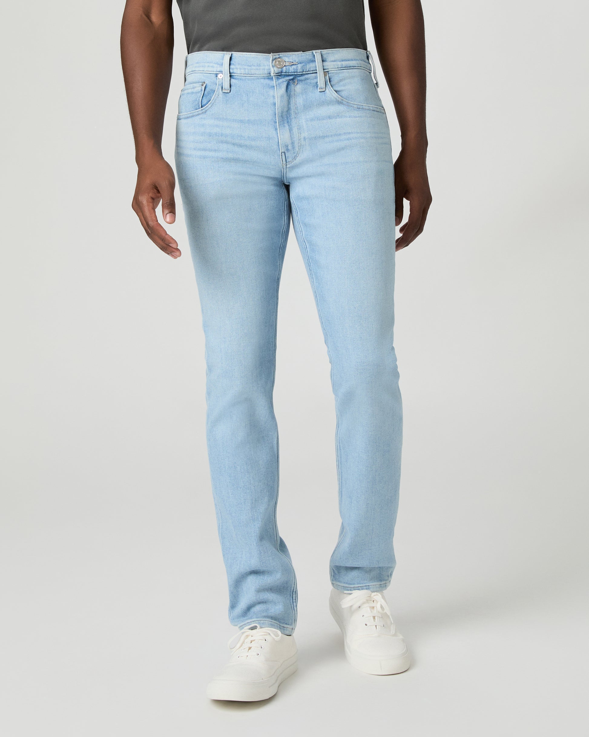 Man wearing a gray t-shirt and light blue jeans on a white background