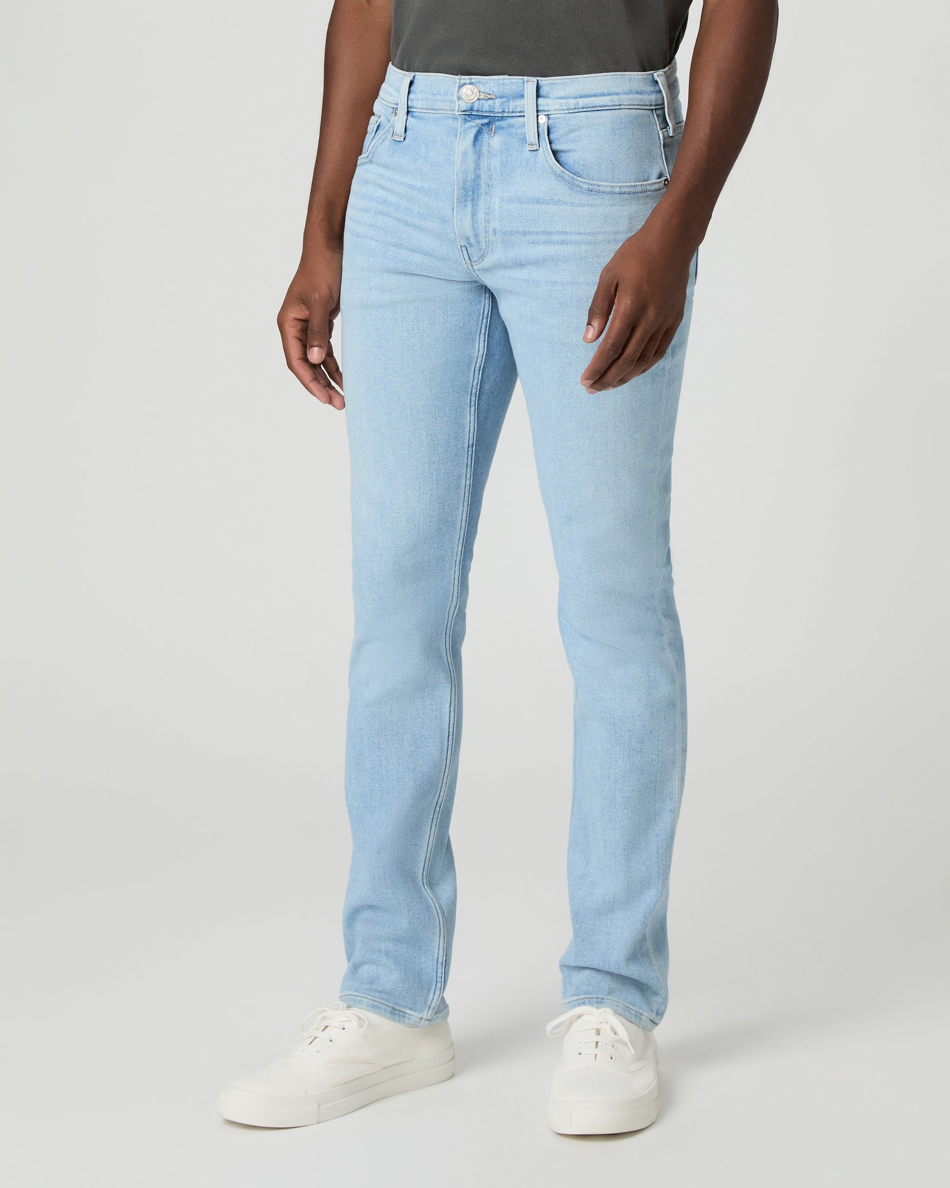 Man wearing a gray t-shirt and light blue jeans on a white background