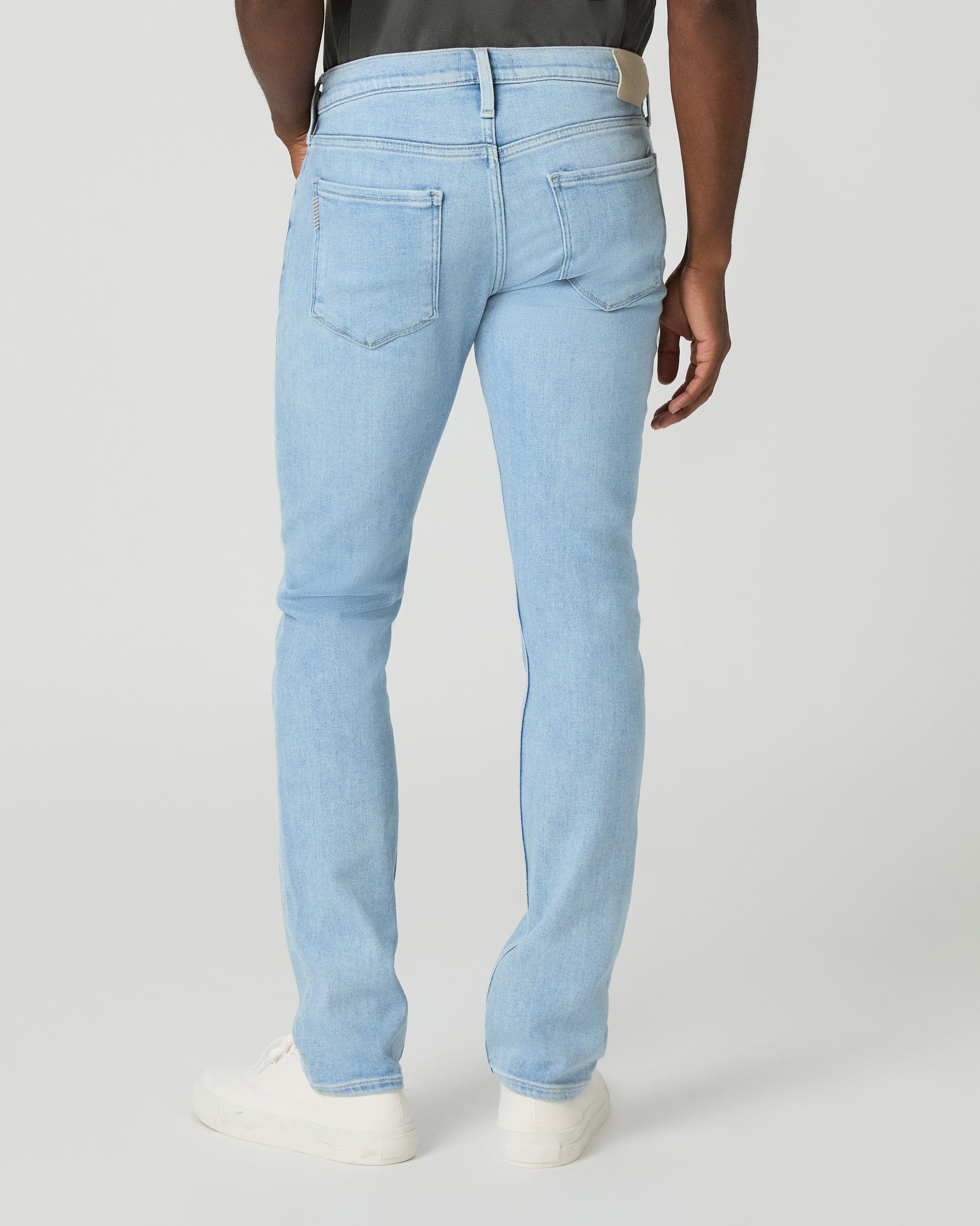 Man wearing a gray t-shirt and light blue jeans on a white background