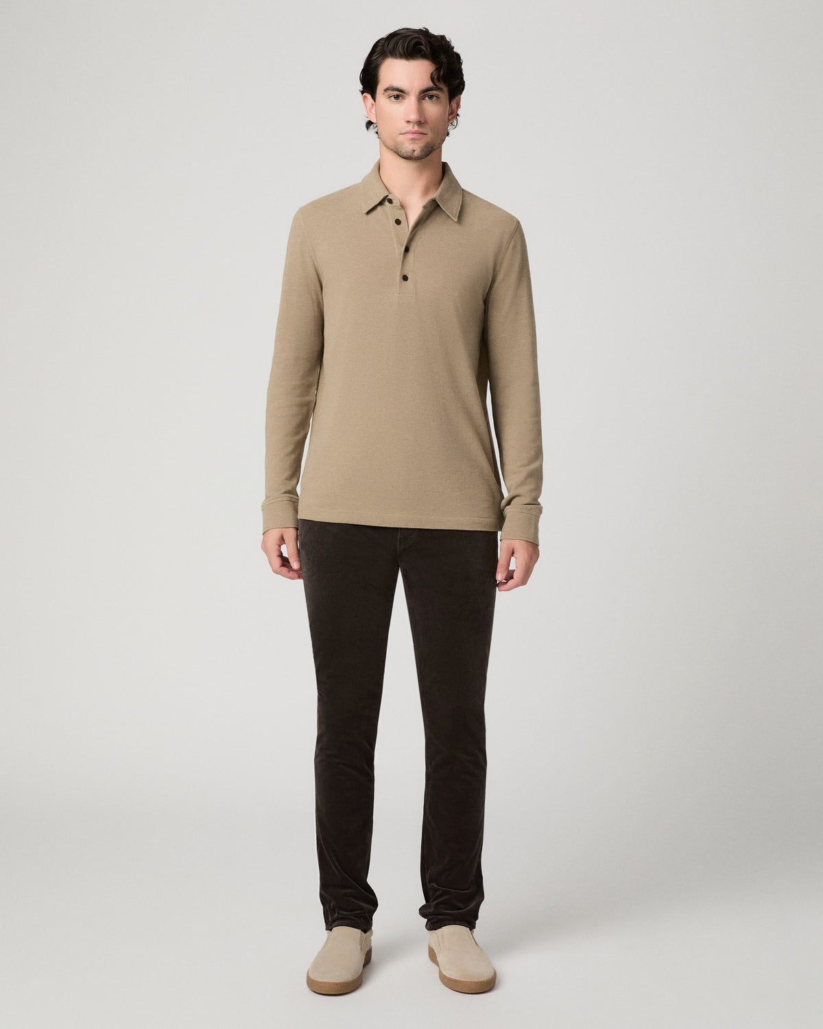 Man wearing beige top and brown pants against a white background