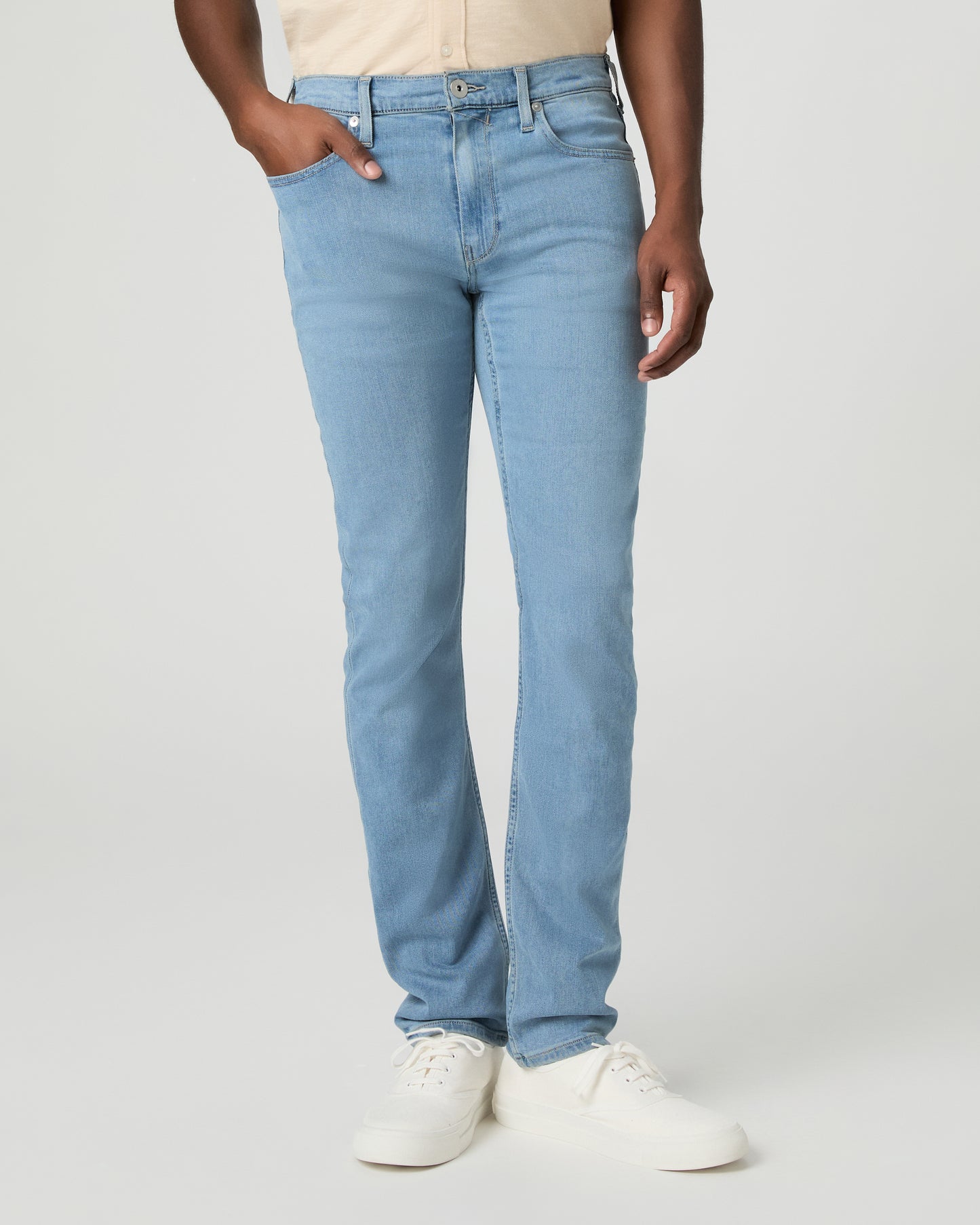 Man wearing a beige shirt and blue jeans on a white background
