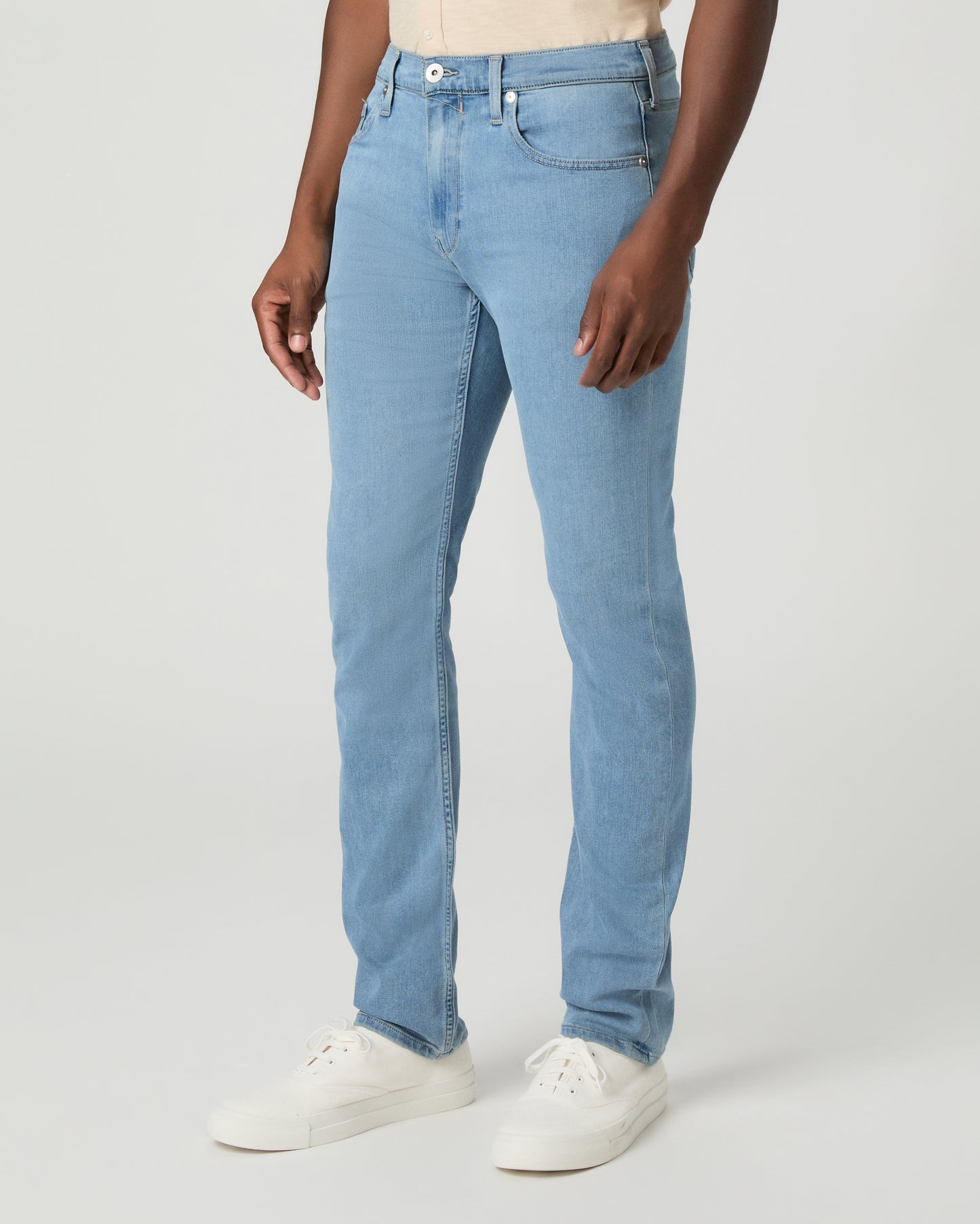 Man wearing a beige shirt and blue jeans on a white background