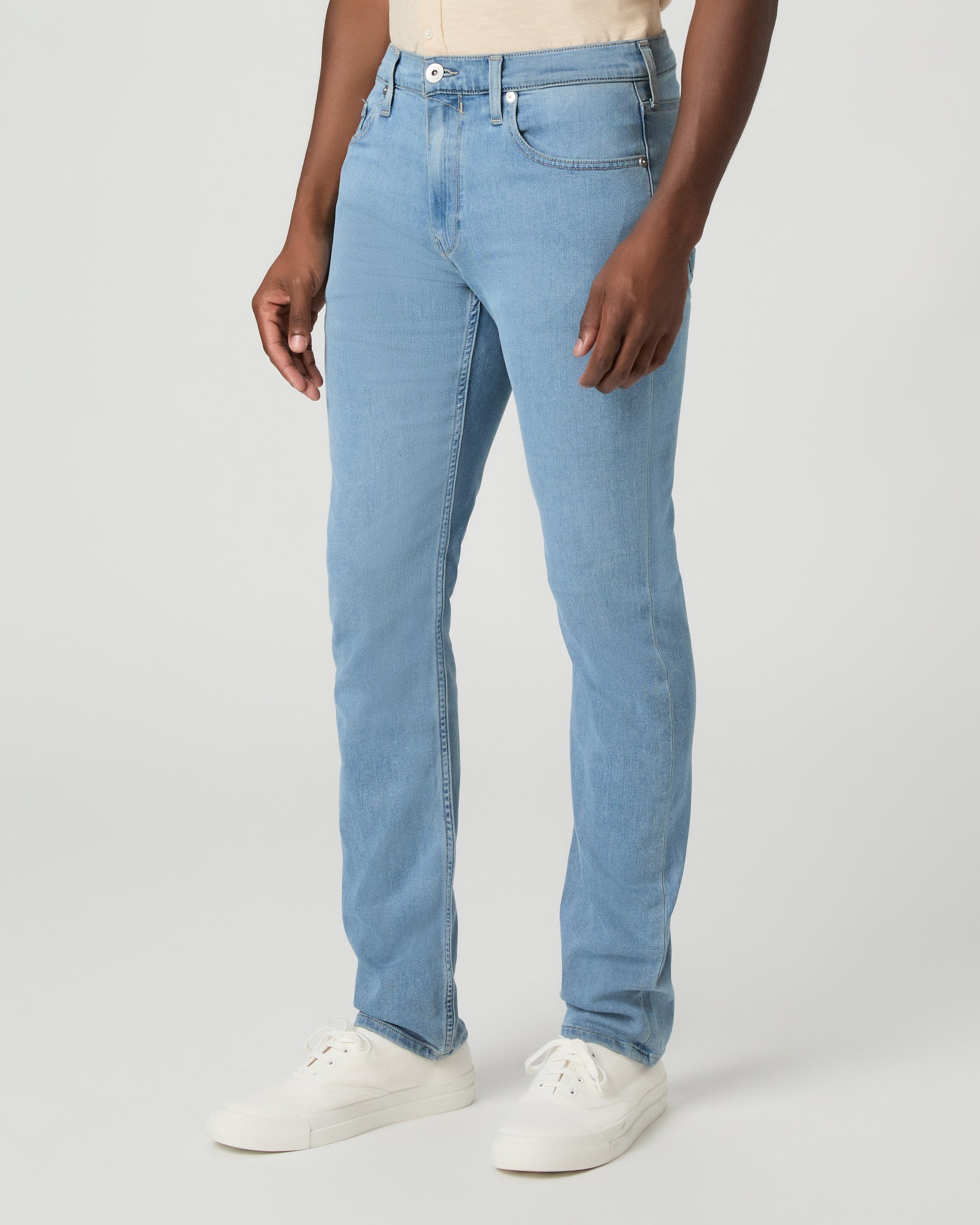 Man wearing a beige shirt and blue jeans on a white background