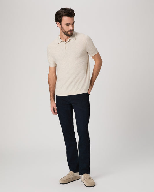 Man wearing a beige polo shirt and dark pants on a white background