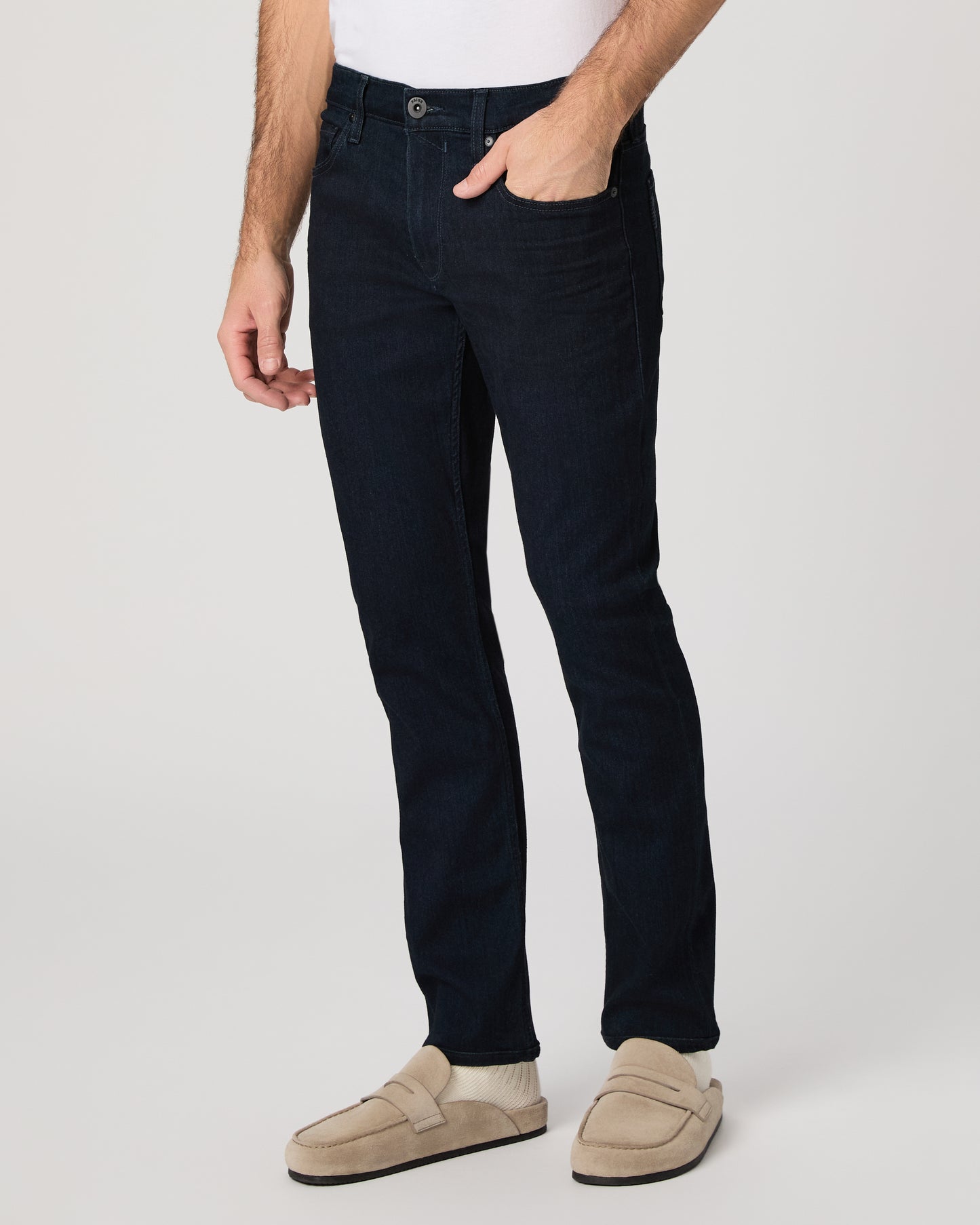Man wearing a beige polo shirt and dark pants on a white background