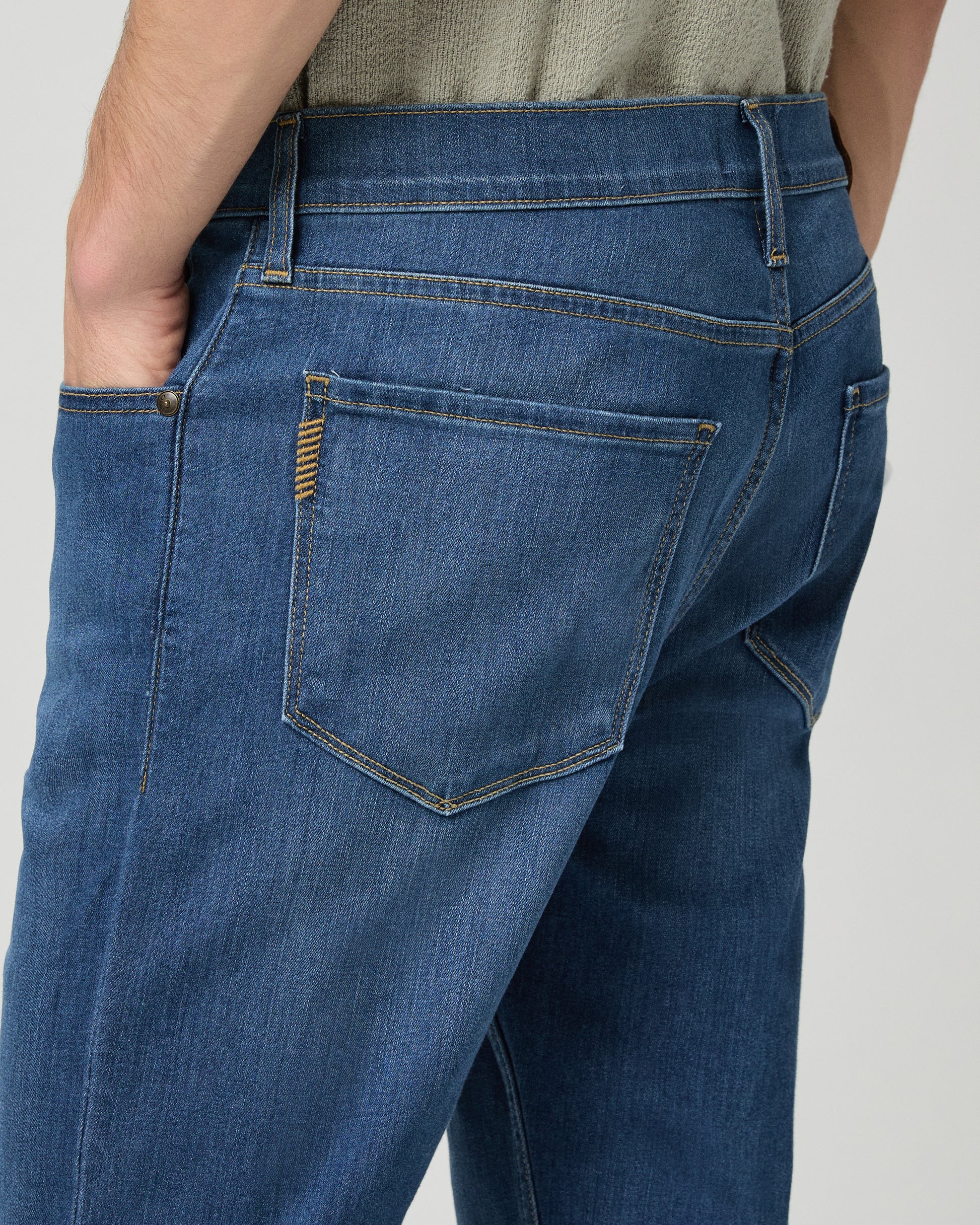 Man wearing a light green shirt and blue jeans on a white background