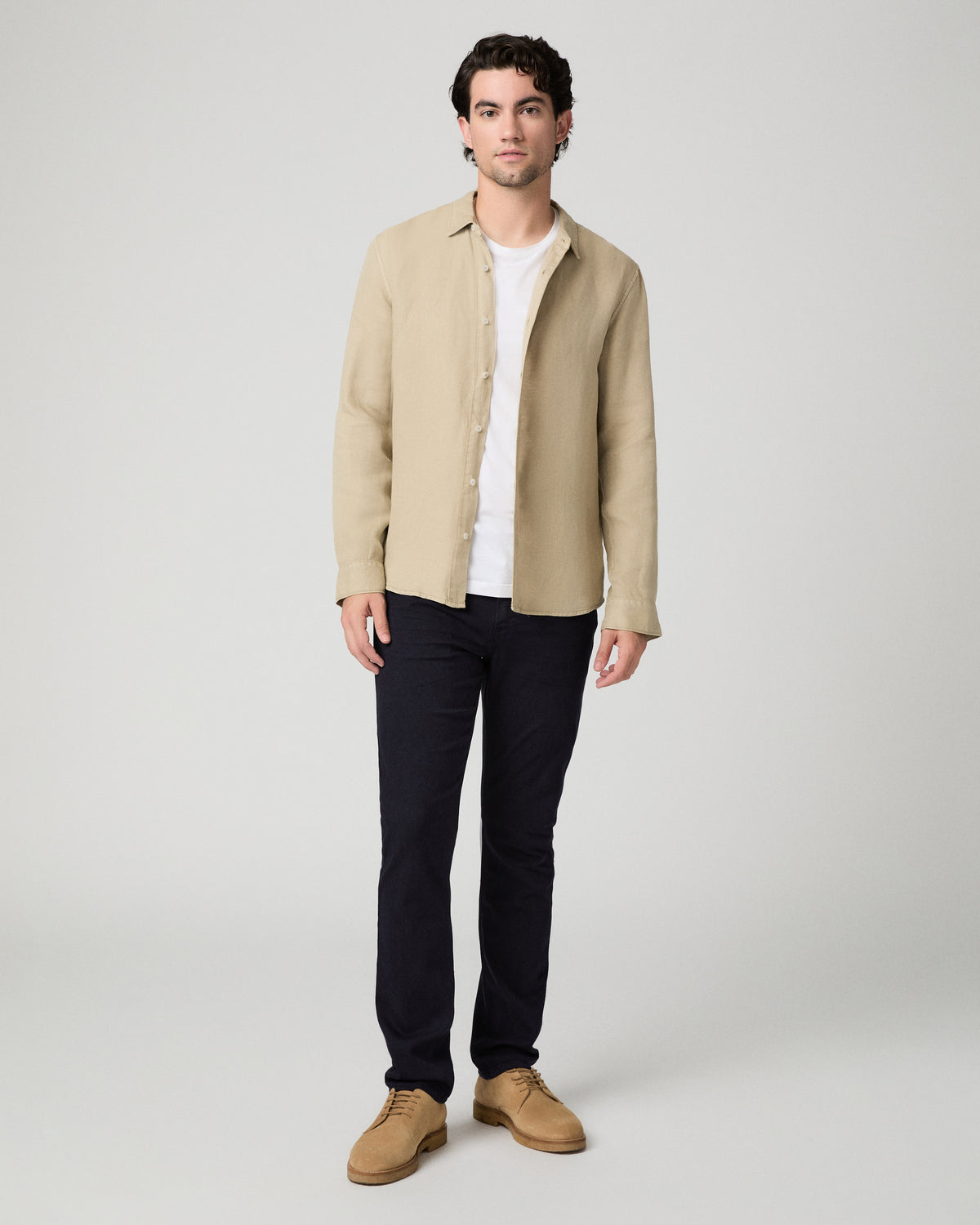 Man wearing beige jacket and a white shirt and blue pants against a white background