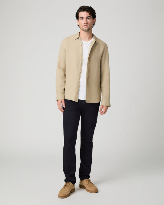 Man wearing beige jacket and a white shirt and blue pants against a white background