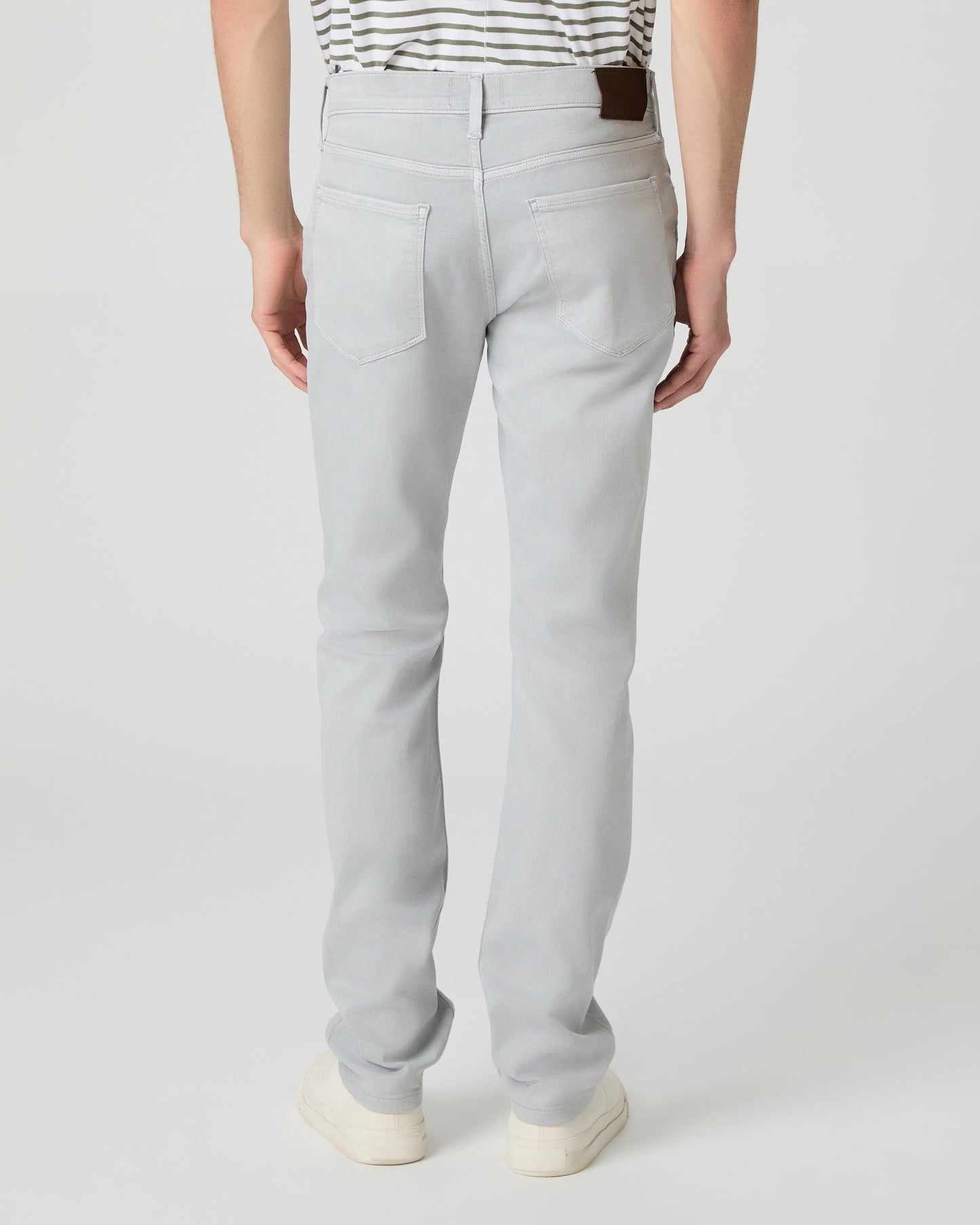 Man wearing a striped shirt and light gray pants on a white background