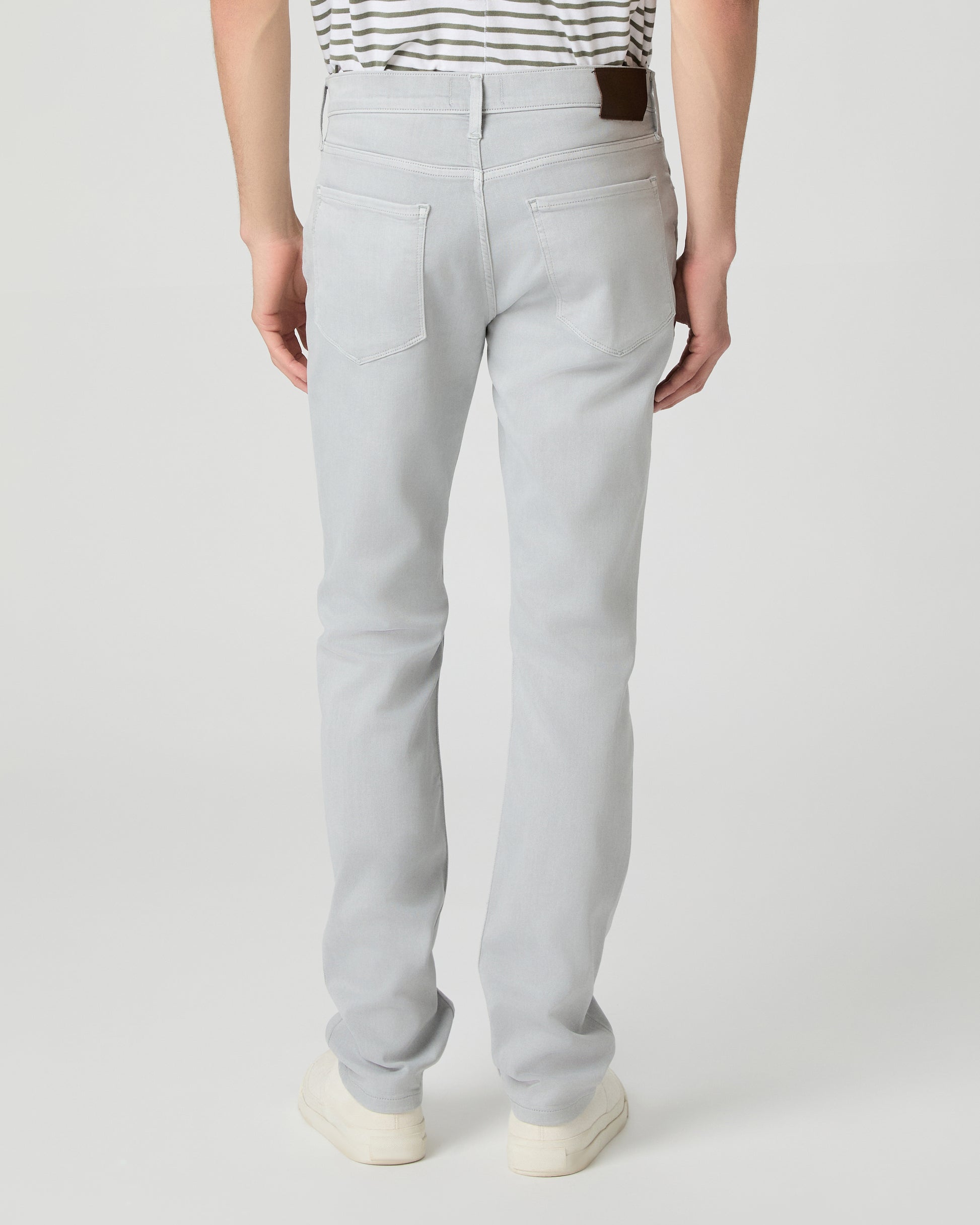 Man wearing a striped shirt and light gray pants on a white background