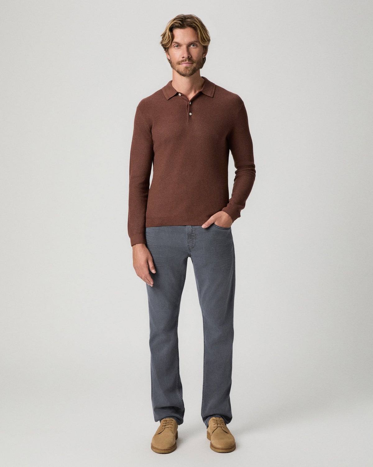 Full-length view of model with one hand in his pocket, wearing a reddish-brown knit polo with the Federal 32 Inch Slim Straight Jean in Vintage Icy River and tan suede boots