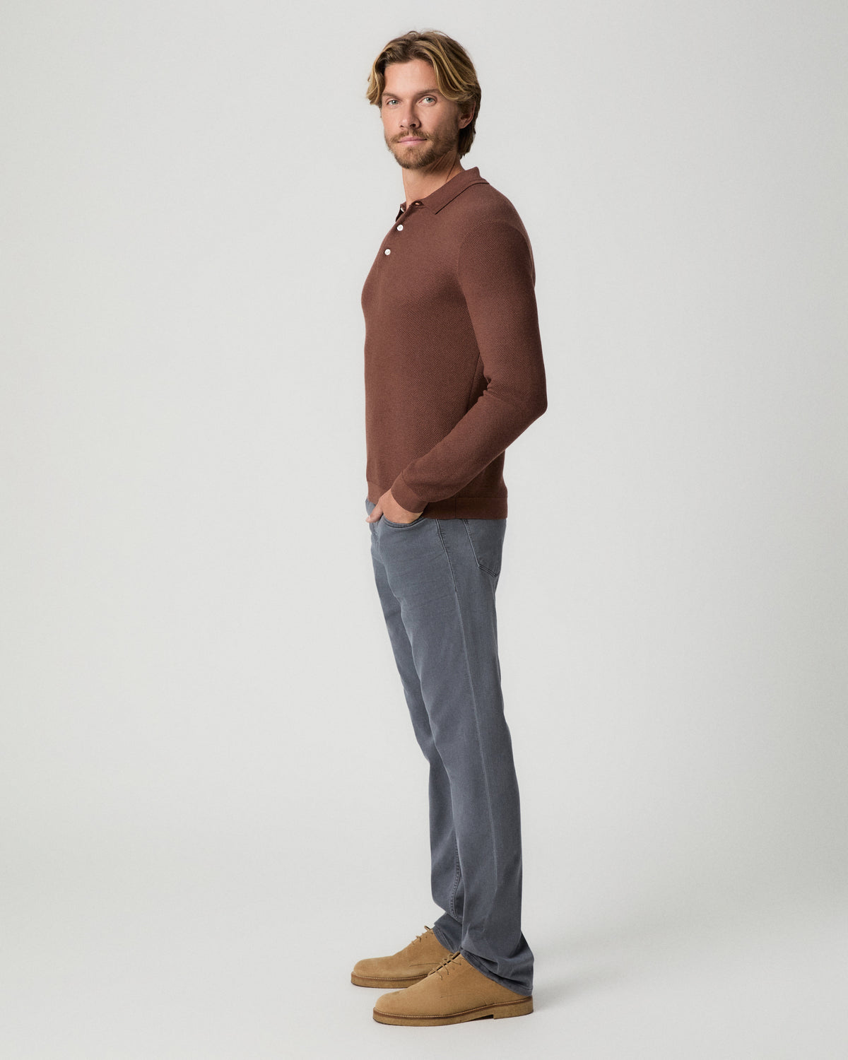 Side profile of model with one hand in his pocket, wearing a reddish-brown knit polo with the Federal 32 Inch Slim Straight Jean in Vintage Icy River and tan suede boots