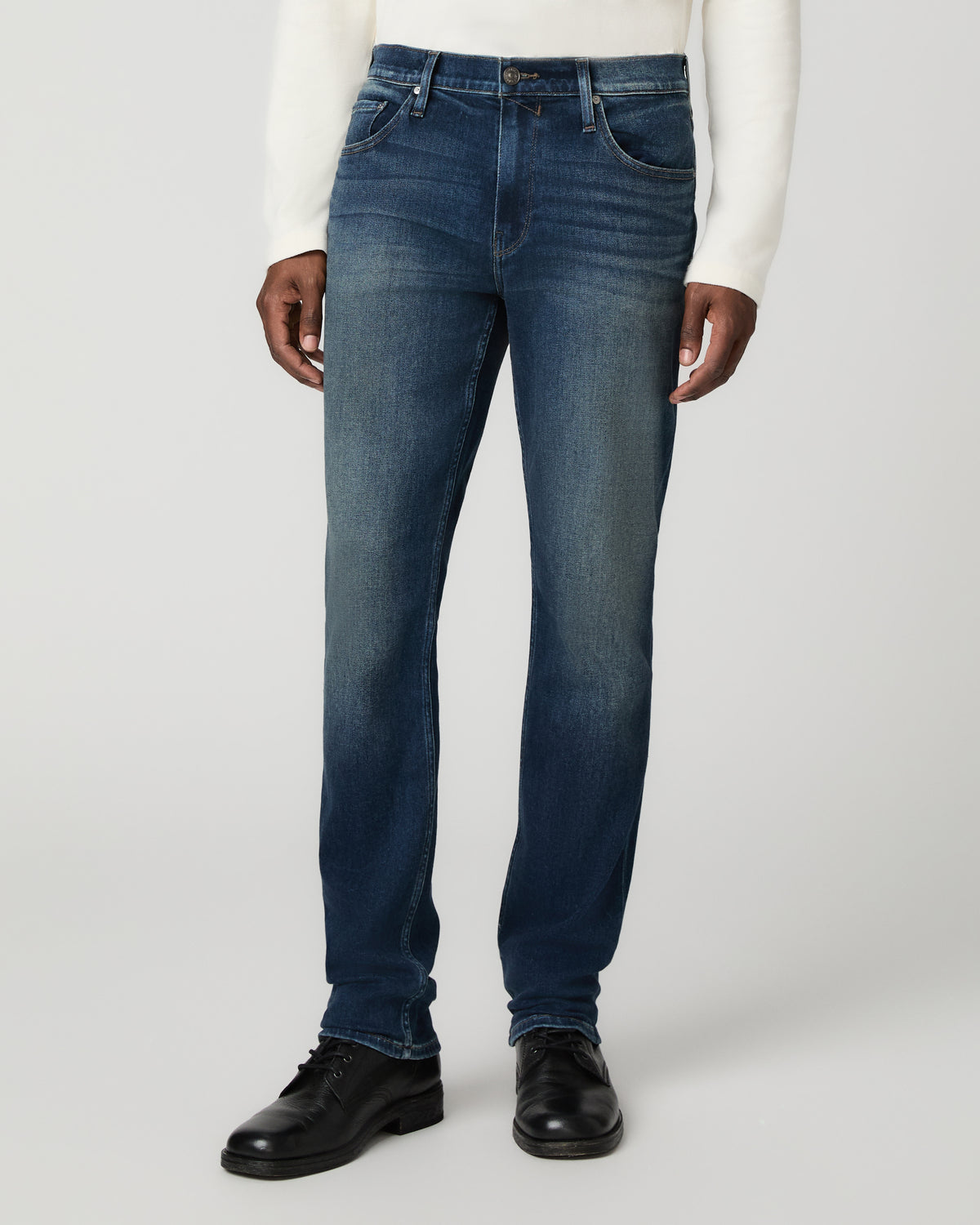 Close front view from the waist down of the slim straight jeans with subtle fading across the thighs, one hand tucked in the pocket.