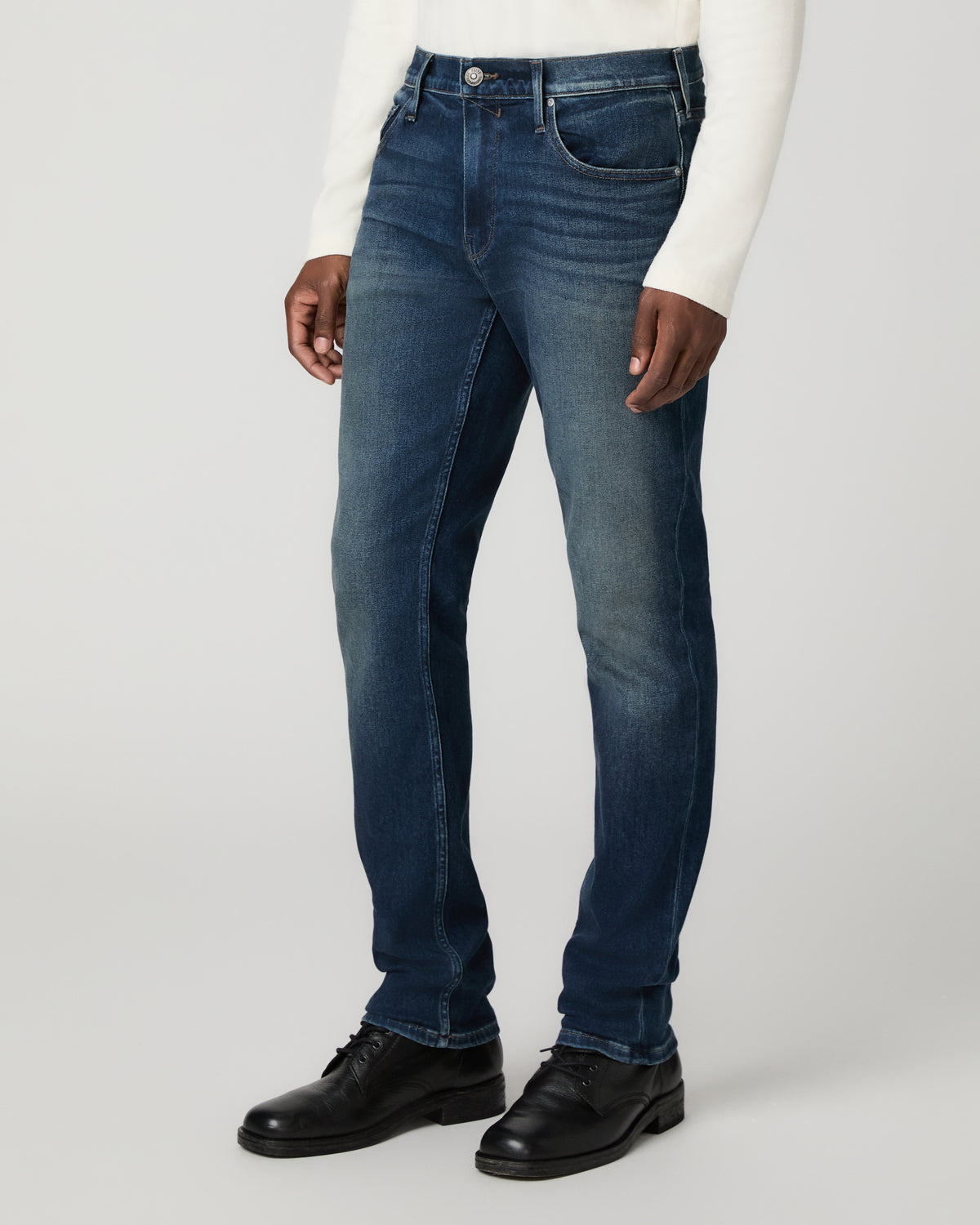 Angled three-quarter front view from the waist down showing the slim straight leg silhouette, paired with black leather shoes.