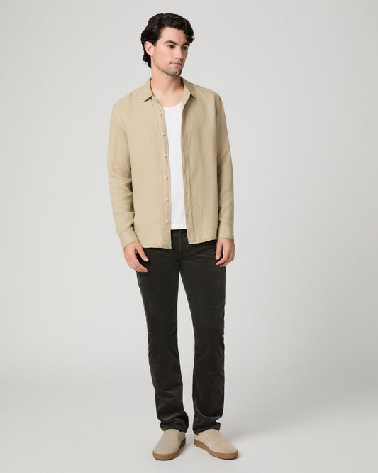 Man wearing beige jacket, white top and black pants against a white background