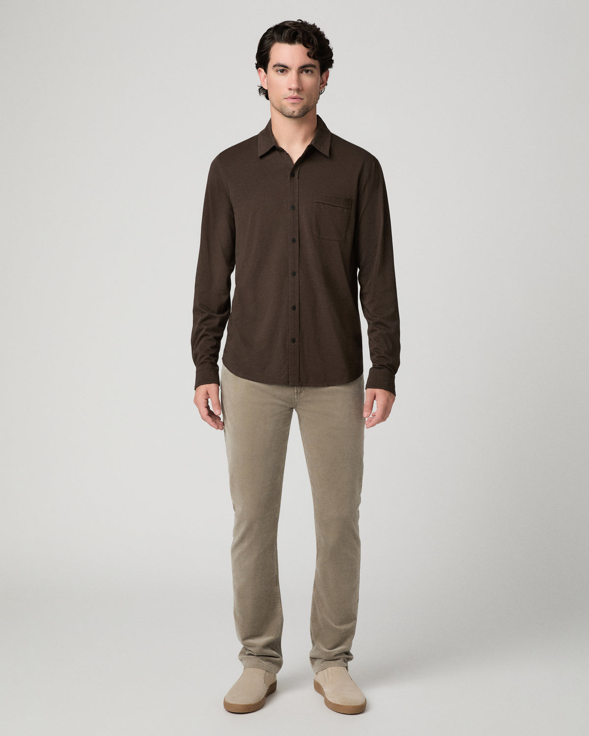 Man wearing brown top and beige pants against a white background