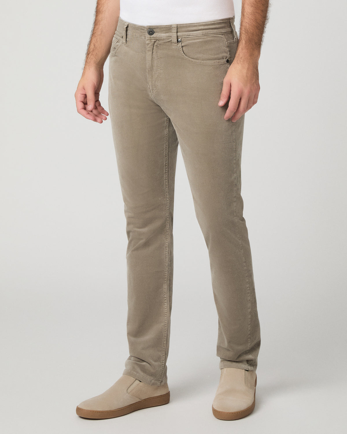 Man wearing white top and beige pants against a white background
