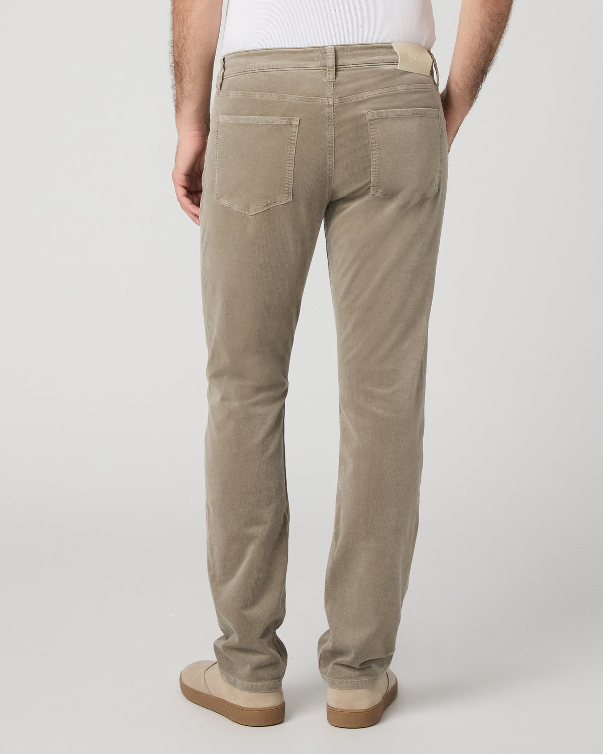 Man wearing white top and beige pants against a white background