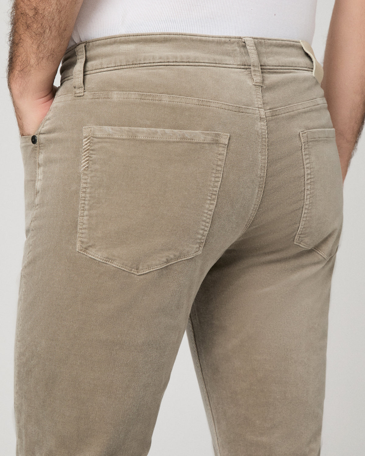 Man wearing white top and beige pants against a white background