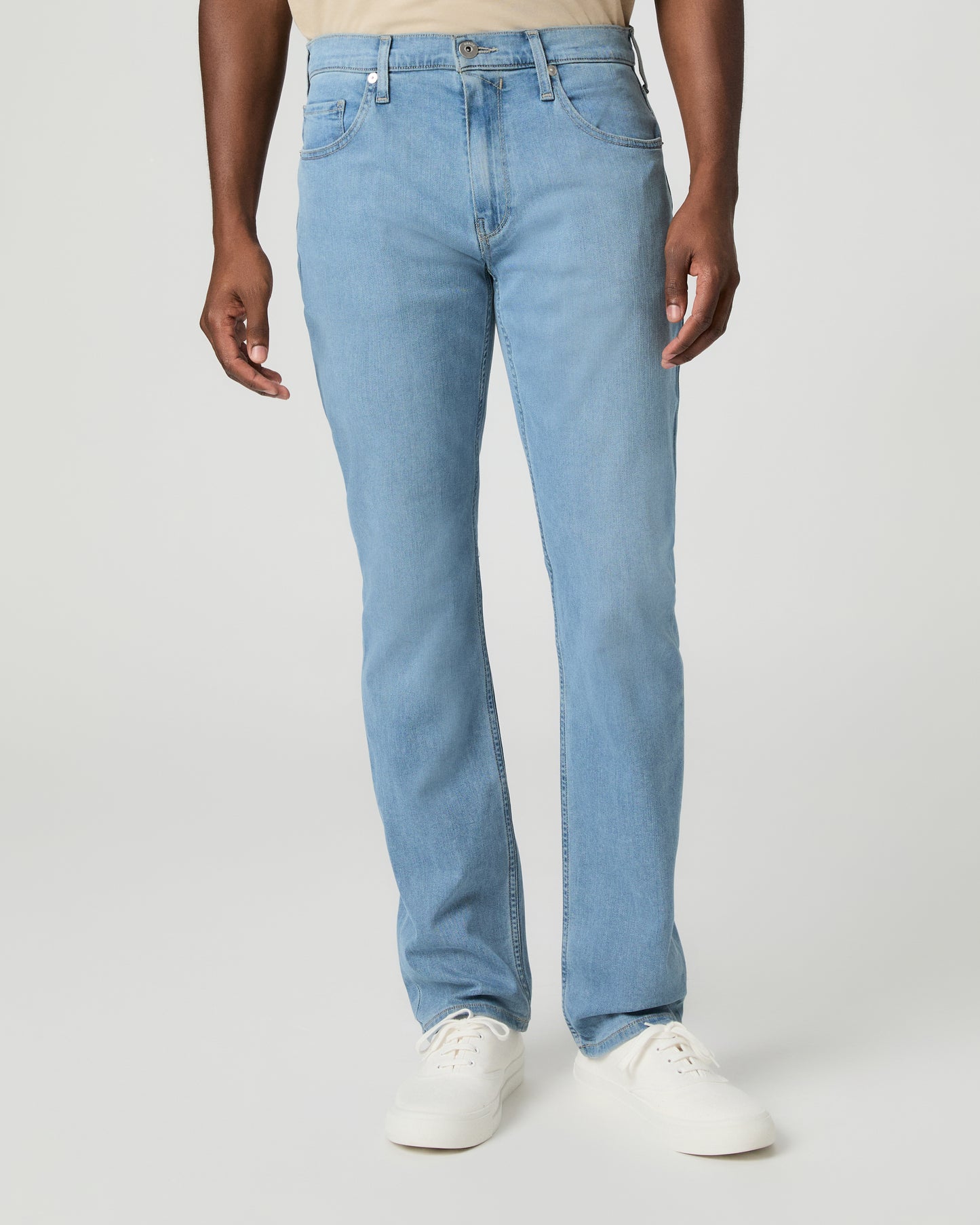 Man wearing a beige t-shirt, light blue jeans on a white background